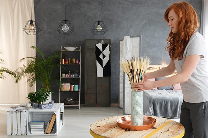 A young woman decorating a living room space with modern decor.