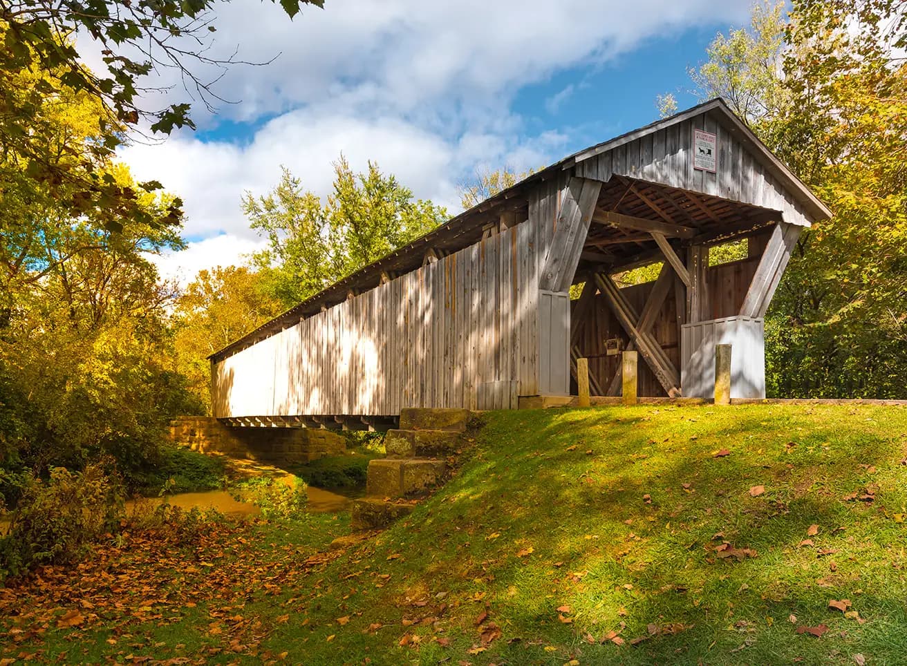An old, covered wooden bridge with a road.