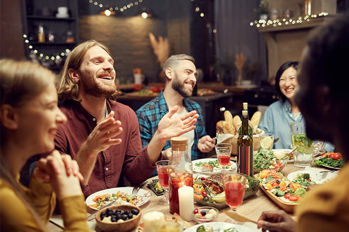Friends laughing around a table with food in a restaurant.