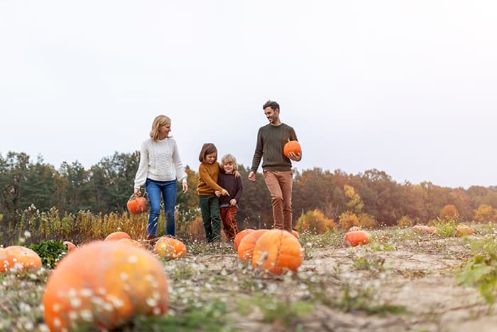 Family picking pumpkins at a fall patch near Columbus apartments, enjoying Halloween seasonal activities in the community.