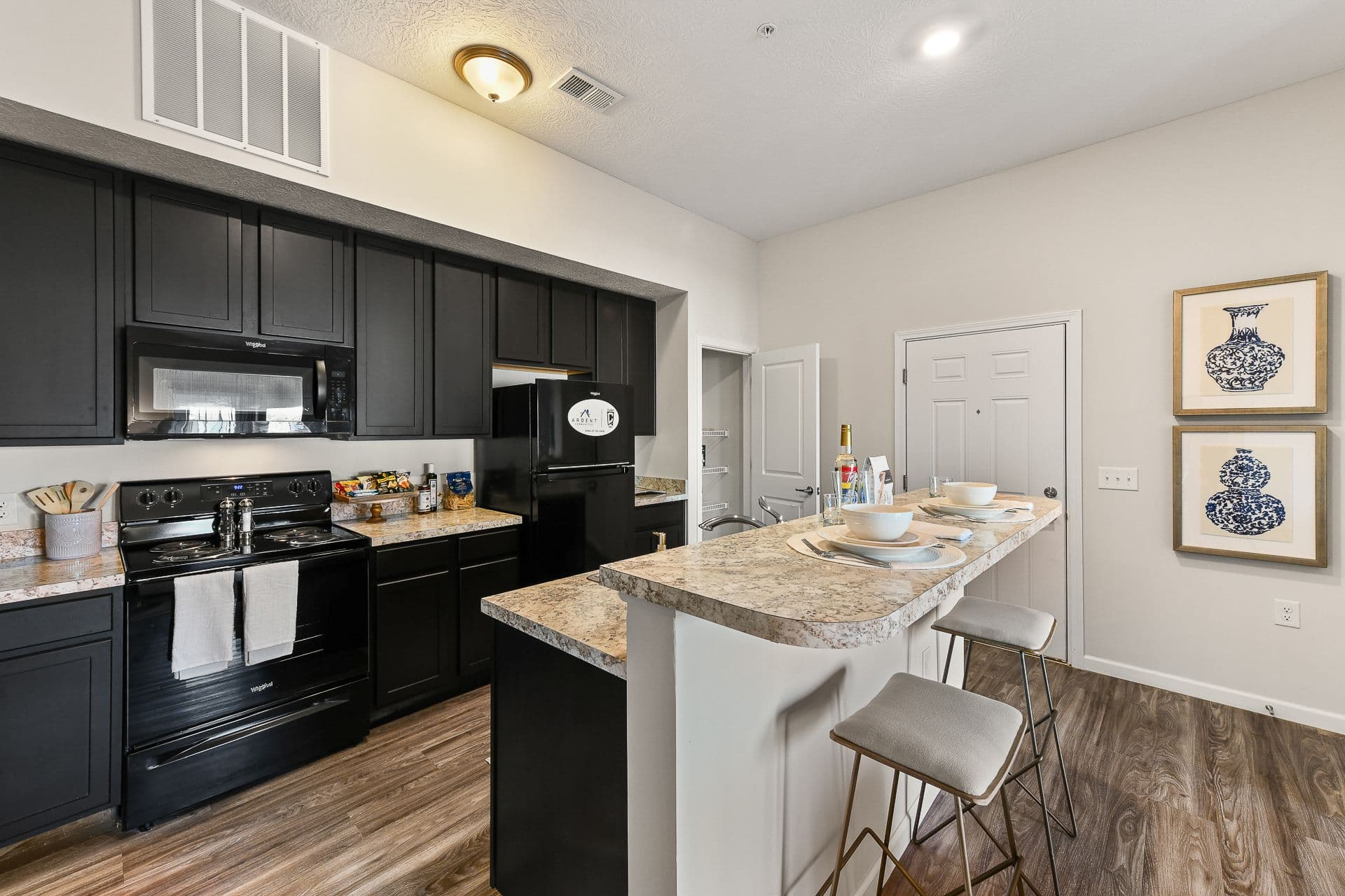 An apartment kitchen with a kitchen island and black appliances