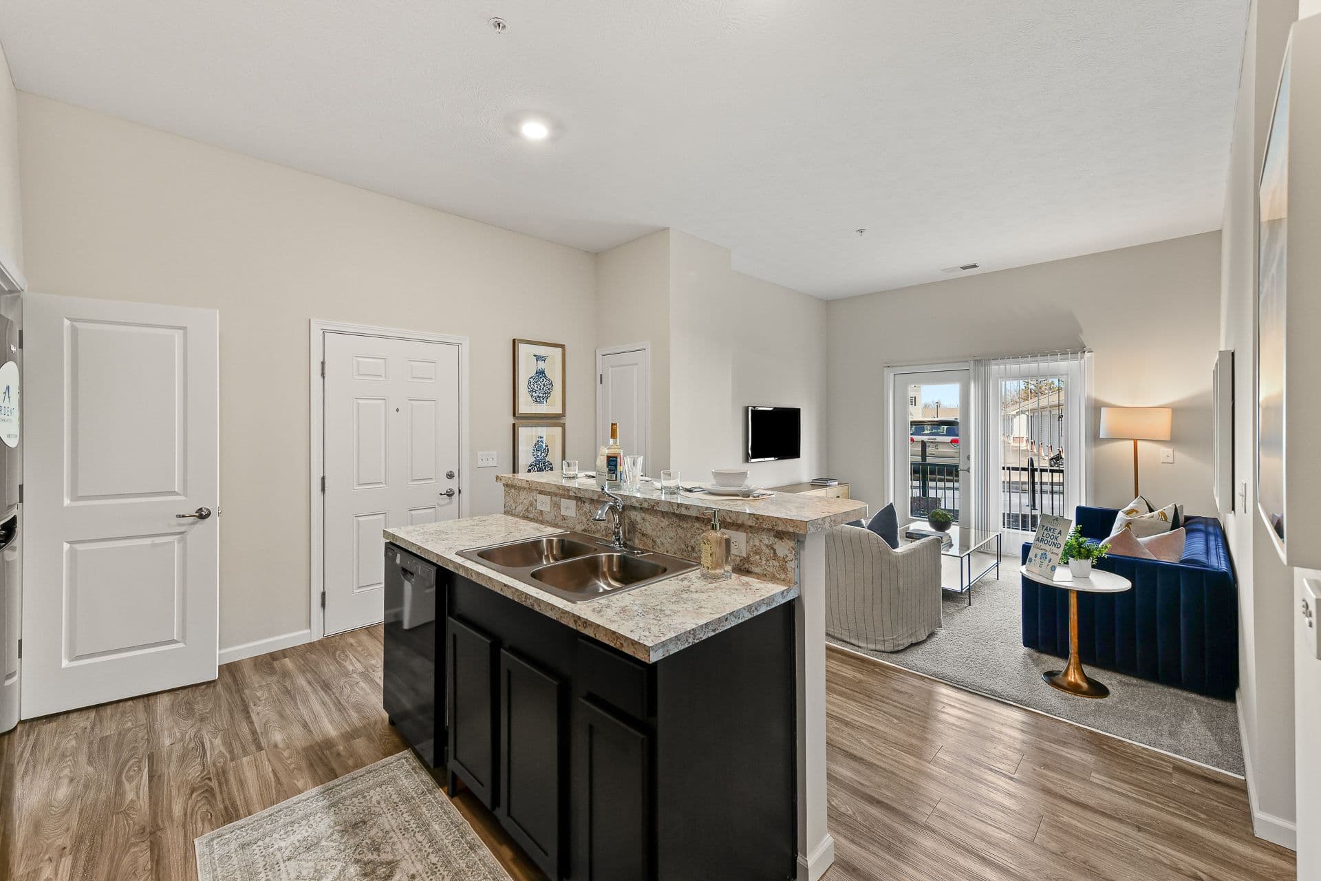 An apartment kitchen with a connecting living room that has a patio