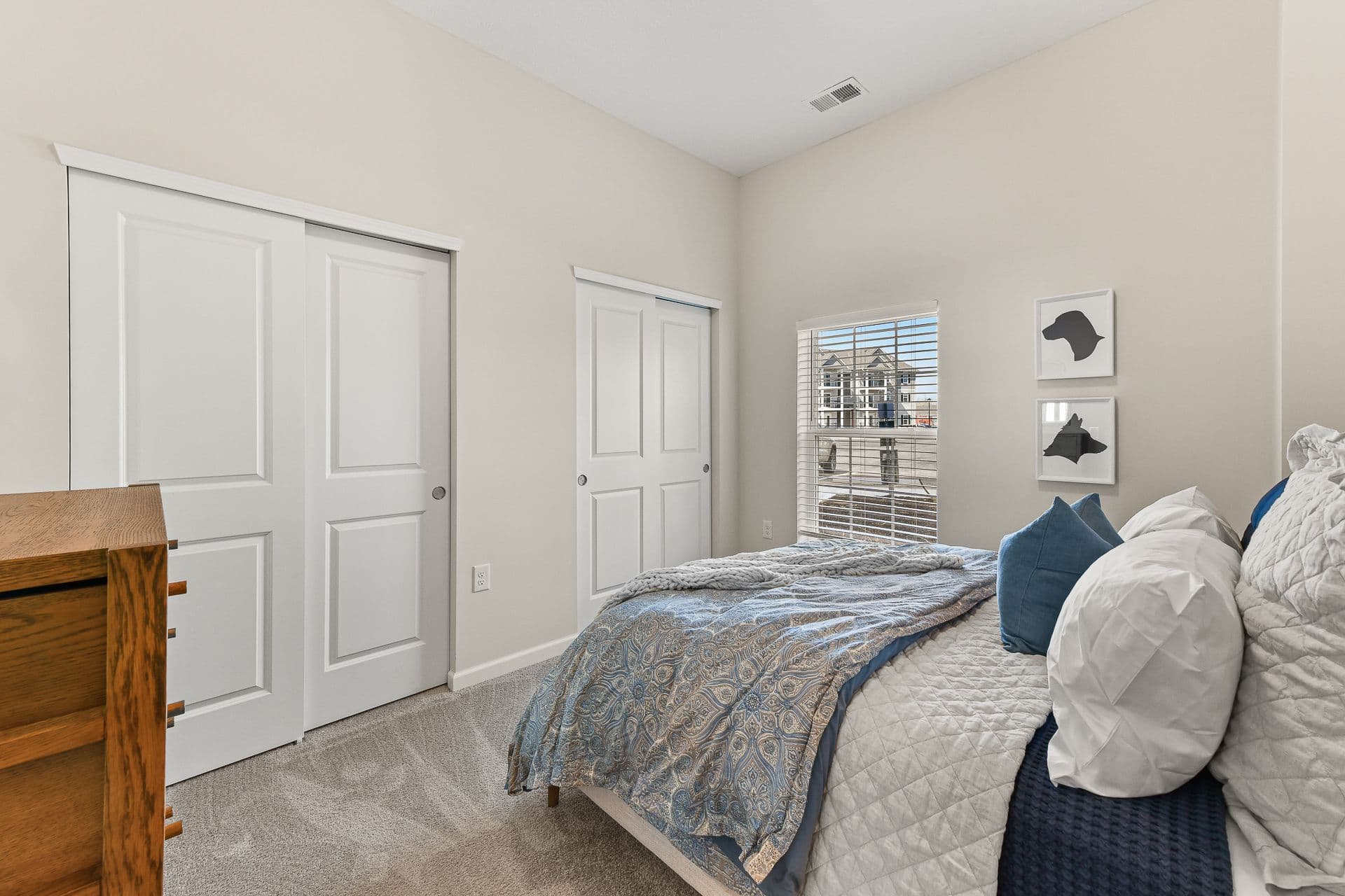 A bedroom with a dresser, bed and wall decor