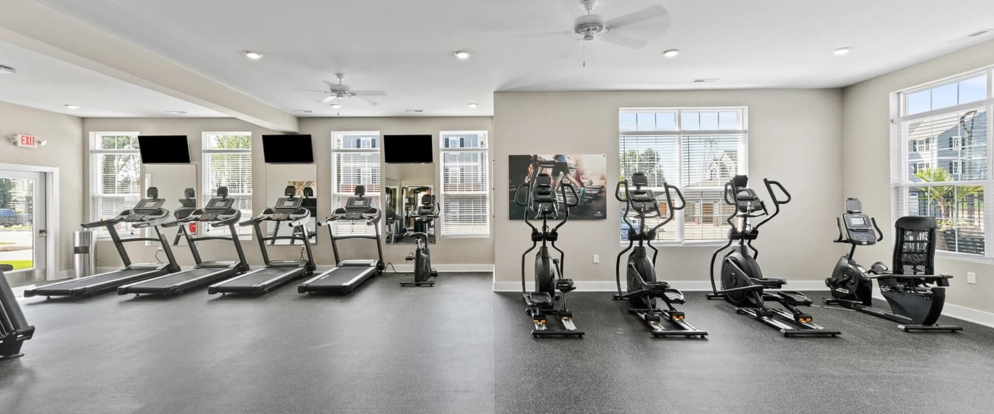 Fitness center with treadmills, ellipticals, and mounted TVs for residents
