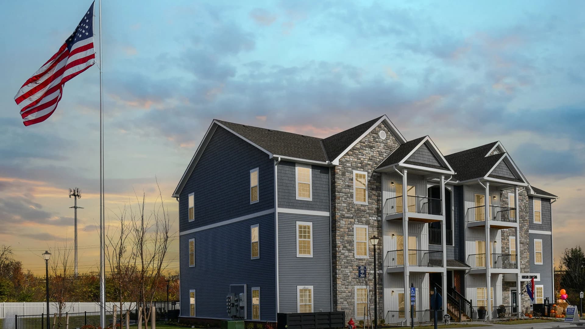 Exterior view at dusk of three story Grove City Ohio apartment complex with American flag hanging from nearby flag pole