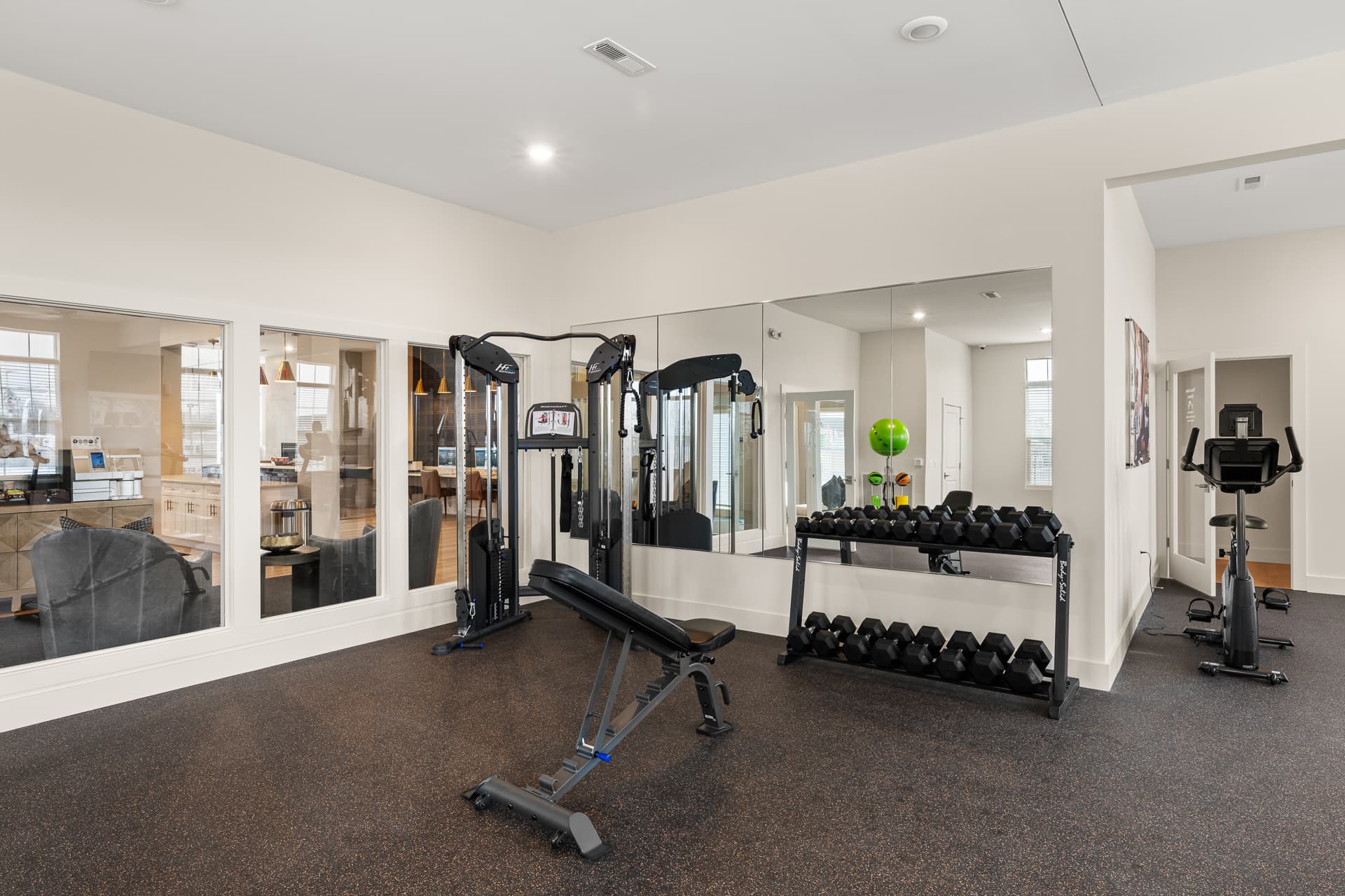 Apartment gym weight room with cable machine, dumbbells, and exercise bike