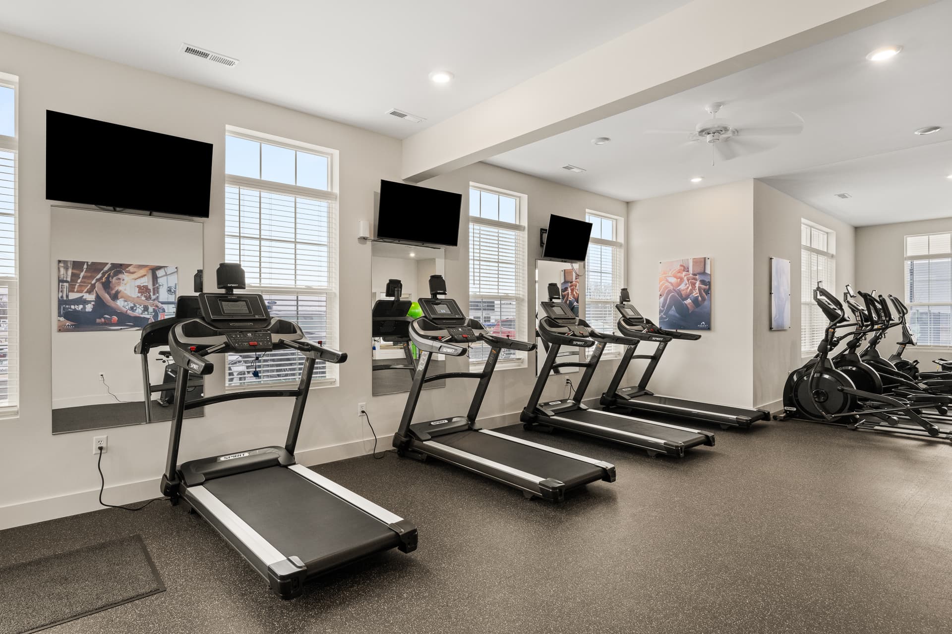 Apartment fitness center with treadmills, ellipticals, and wall-mounted TVs