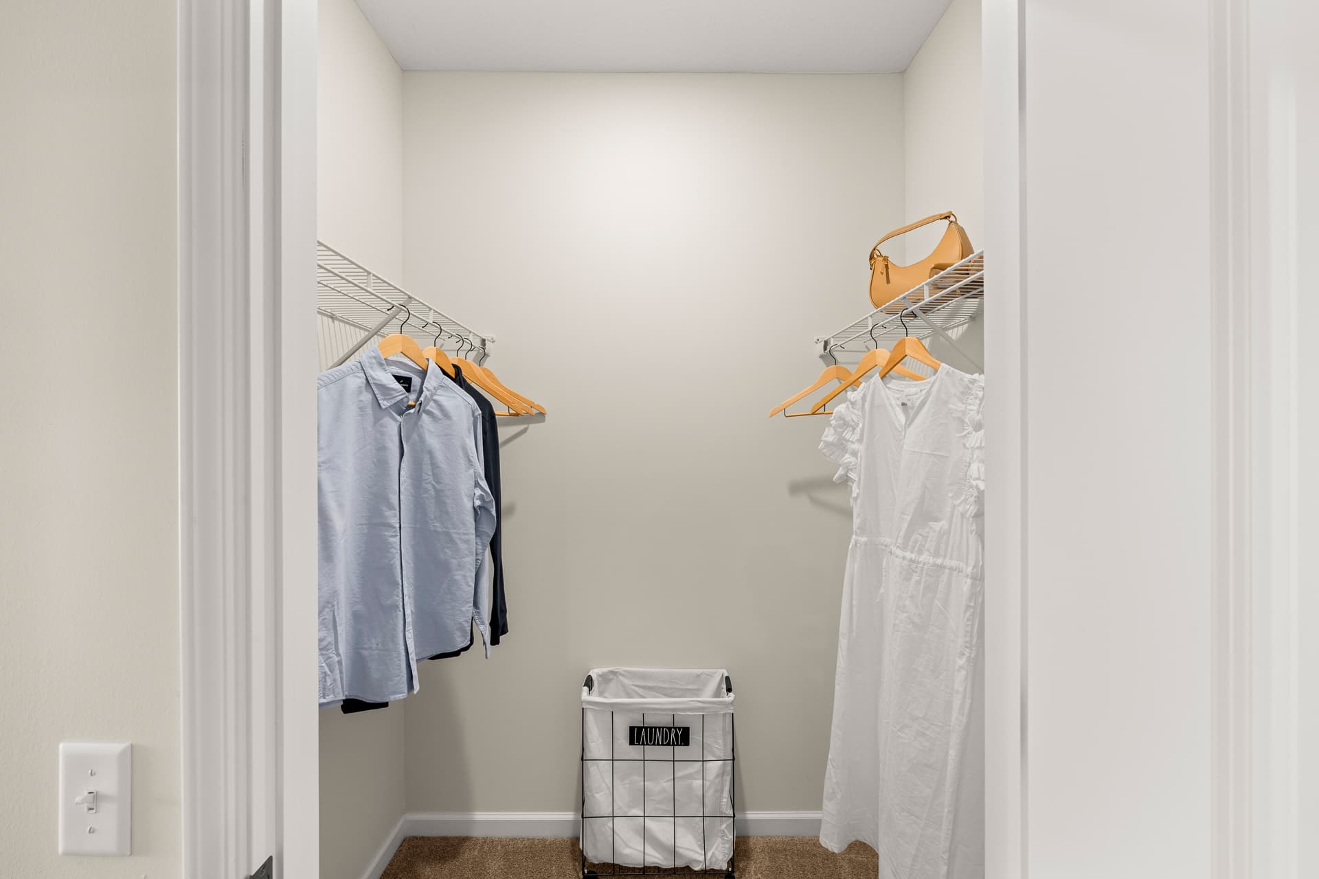 Spacious apartment walk-in closet with dual clothing rods and laundry basket