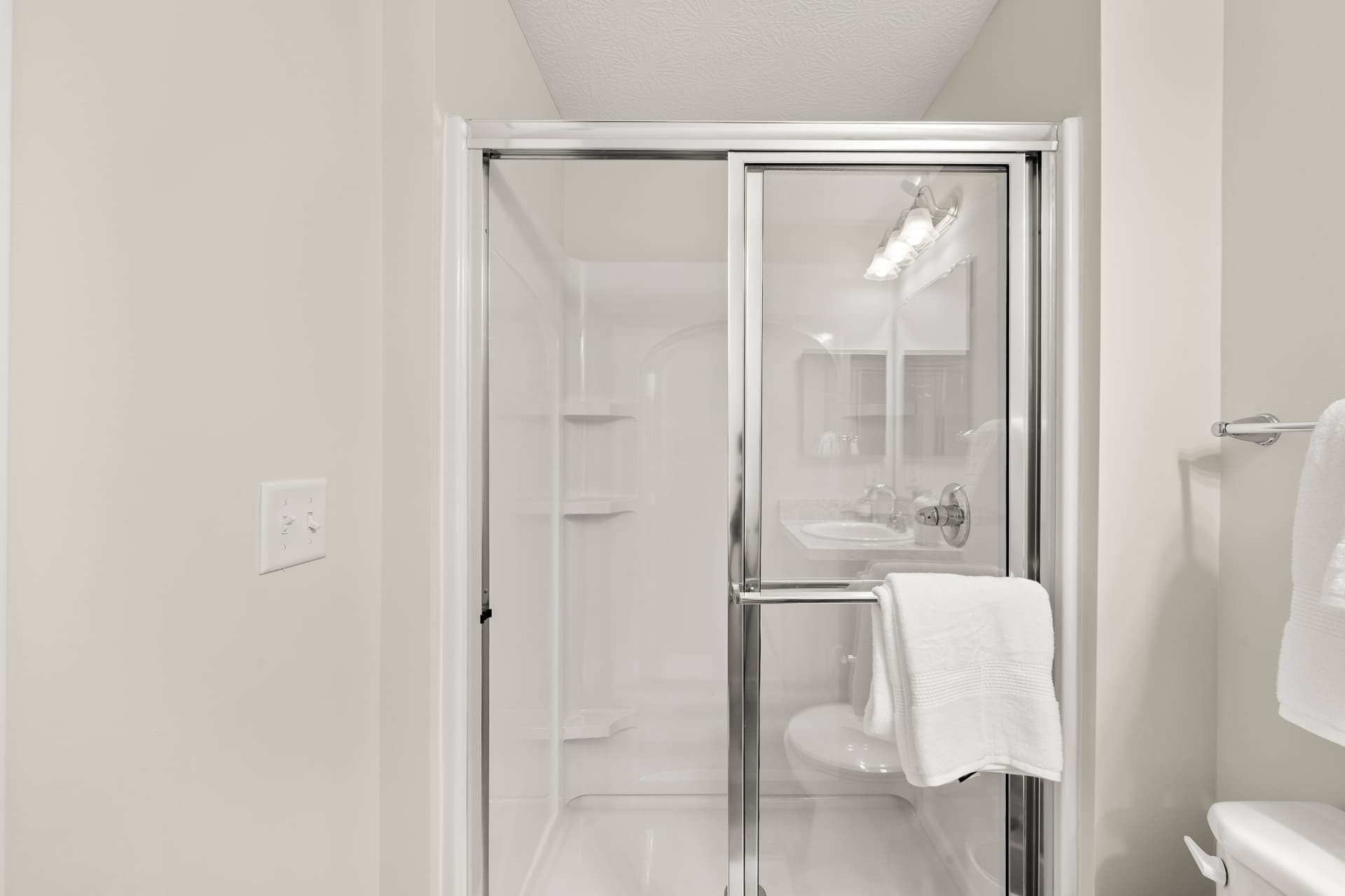 Clean walk-in shower with glass sliding door in an Ardent apartment bathroom