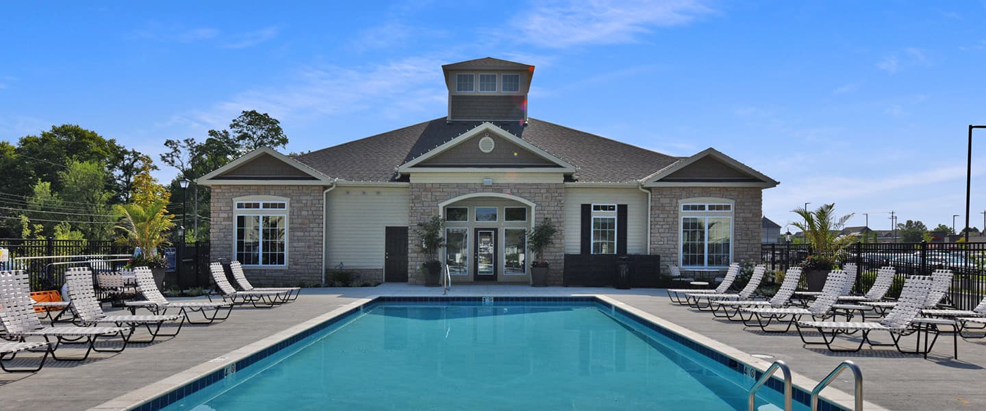 Outdoor pool at Woodfield Park with lounge chairs surrounding it near the clubhouse