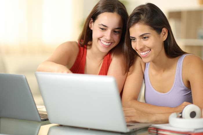 A woman showing and asking questions from her laptop to another woman