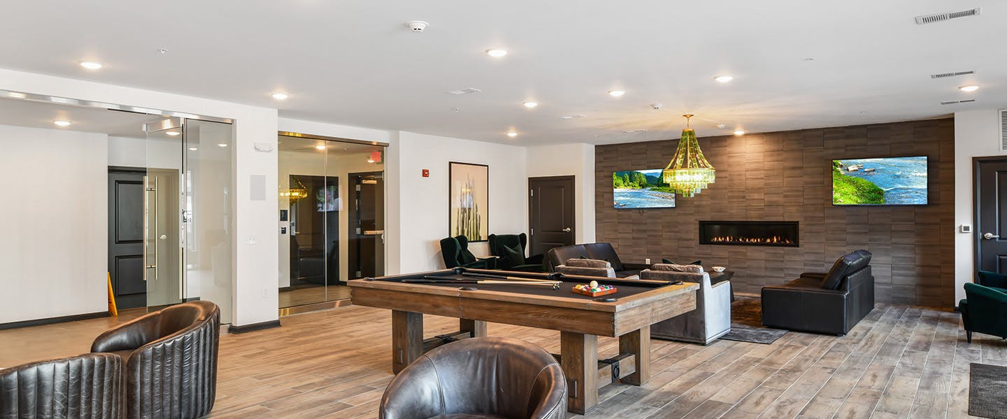 A community space complete with furniture, modern decor, a fireplace and pool table.