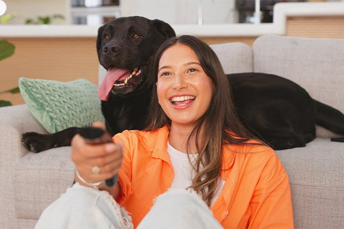 Woman laughing and watching tv with her dog in an apartment living room