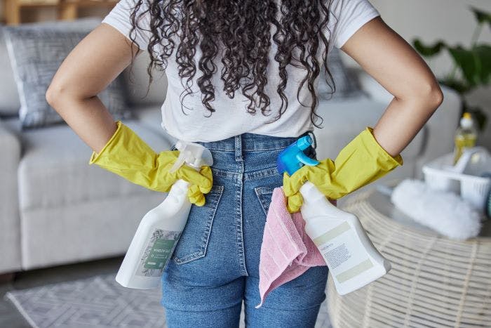 Woman with cleaning products spring cleaning her apartment.