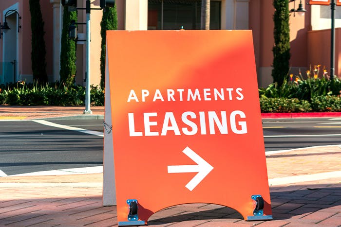Orange apartments leasing sign on a street sidewalk