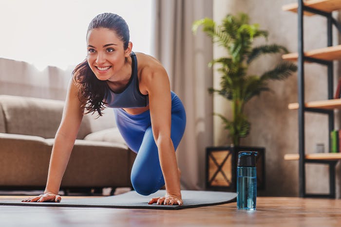 A woman in a blue athletic outfit doing fitness exercises in an apartment living room