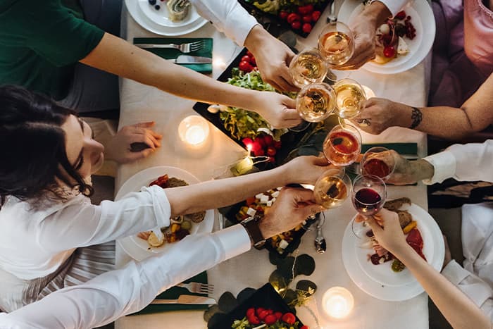 Top view of a midsection of people sitting at a table at an indoor apartment dinner party
