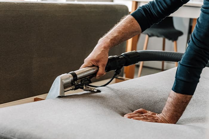 A man deep cleaning a sofa in his apartment
